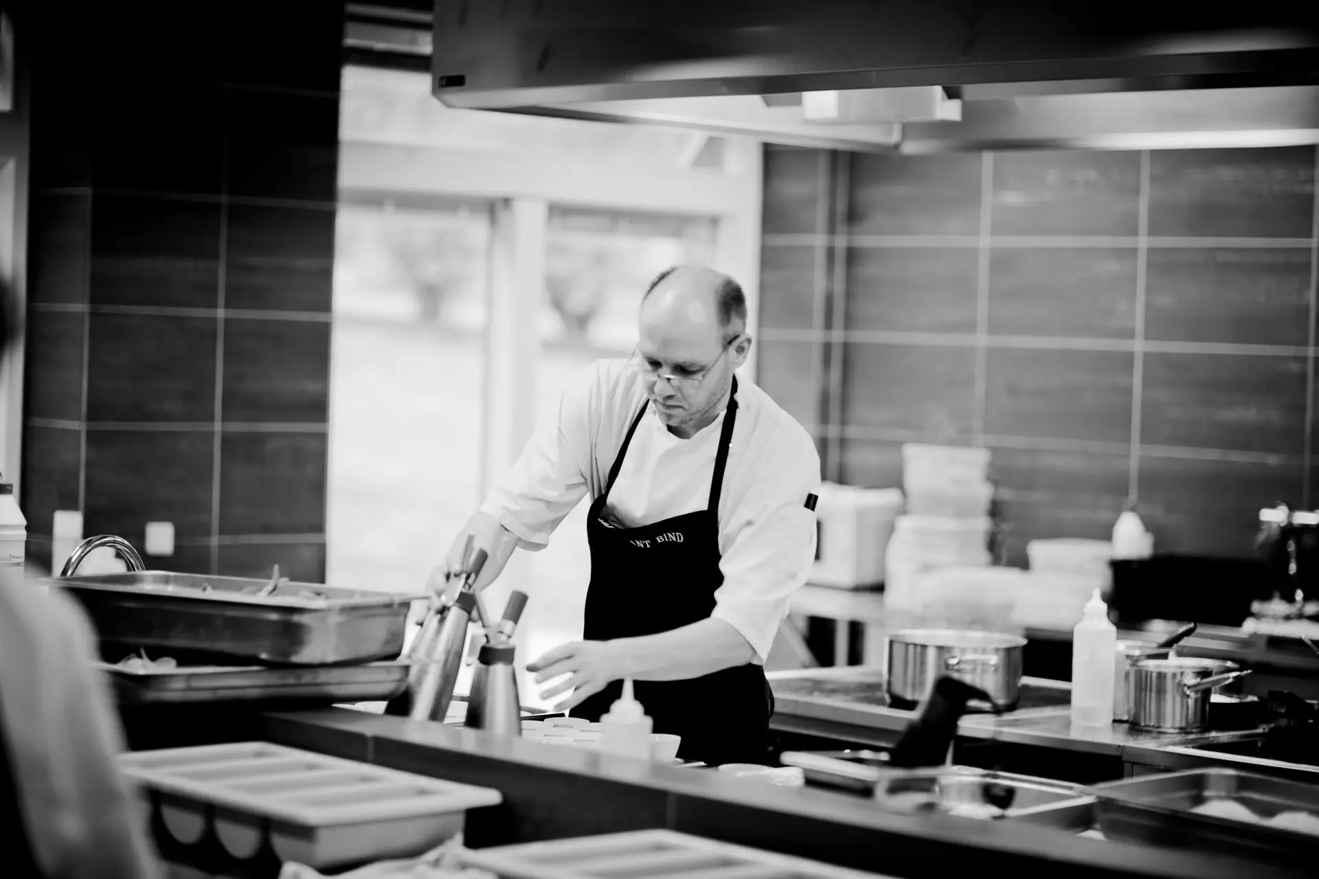 Chef in a restaurant kitchen carefully preparing dishes with attention to detail.
